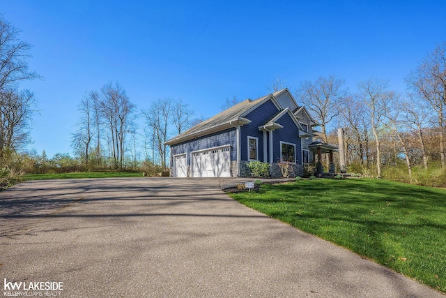 view of side of property featuring an attached garage, aphalt driveway, and a lawn