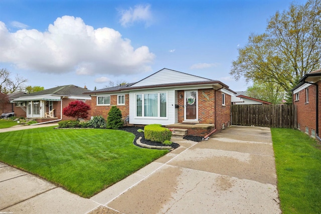 view of front of home featuring brick siding, a front lawn, fence, and driveway
