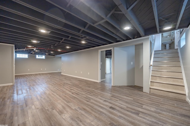 basement featuring baseboards, stairs, and wood finished floors