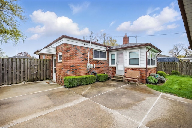 rear view of property featuring fence, a patio, a chimney, brick siding, and entry steps
