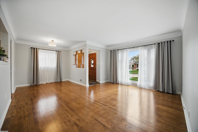 unfurnished living room with plenty of natural light, baseboards, and wood finished floors