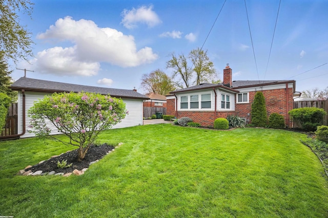 back of property with a yard, brick siding, fence, and a chimney