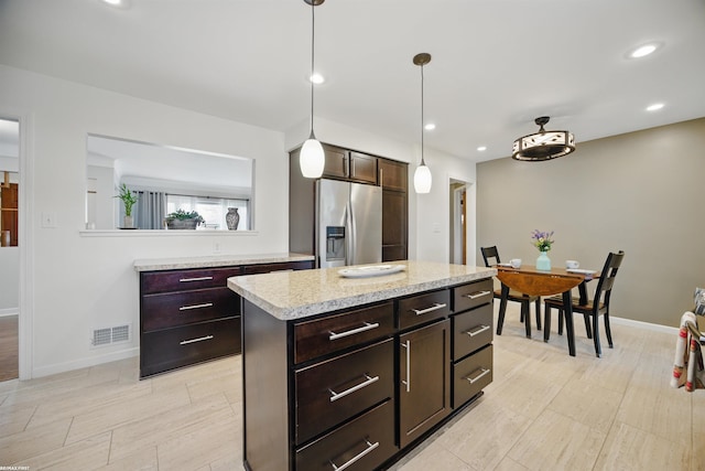 kitchen featuring dark brown cabinetry, light countertops, baseboards, stainless steel refrigerator with ice dispenser, and pendant lighting
