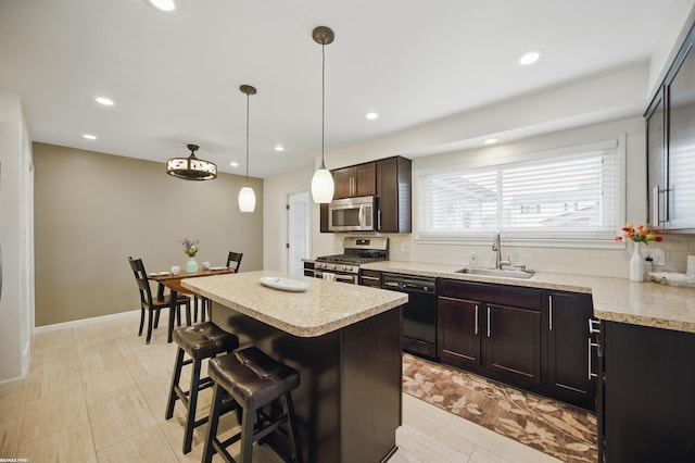 kitchen featuring a kitchen bar, appliances with stainless steel finishes, a center island, a sink, and light countertops