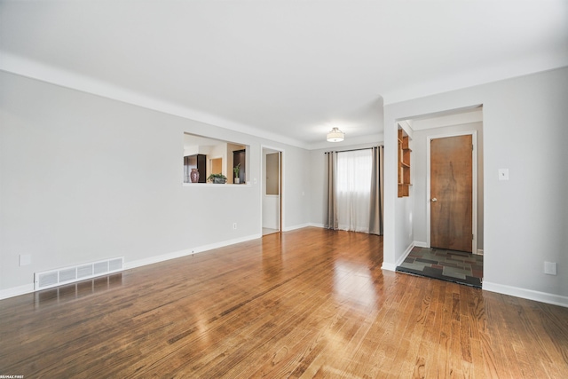 unfurnished living room with baseboards, wood finished floors, and visible vents