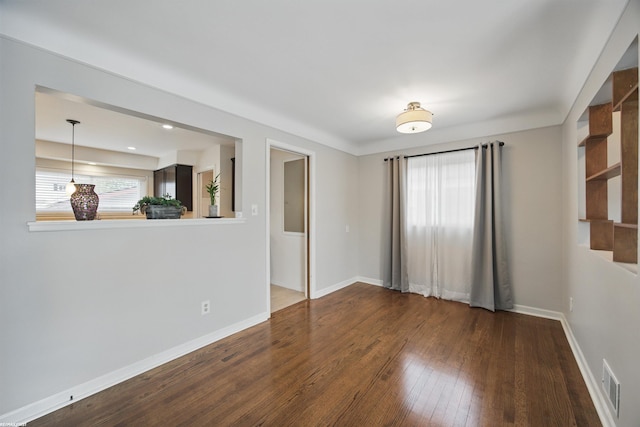 empty room featuring baseboards, hardwood / wood-style flooring, and visible vents