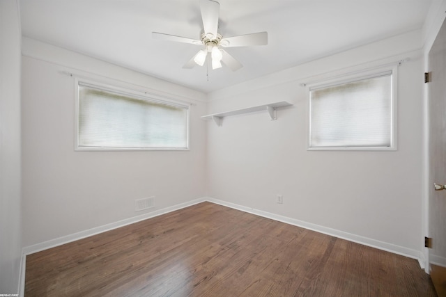 spare room featuring baseboards, ceiling fan, wood finished floors, and visible vents