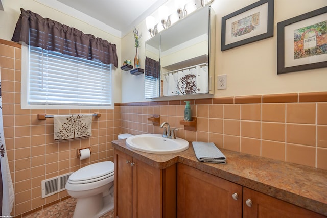 bathroom with visible vents, tile walls, a wainscoted wall, vanity, and toilet