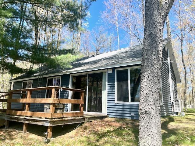 back of house with a deck and a shingled roof