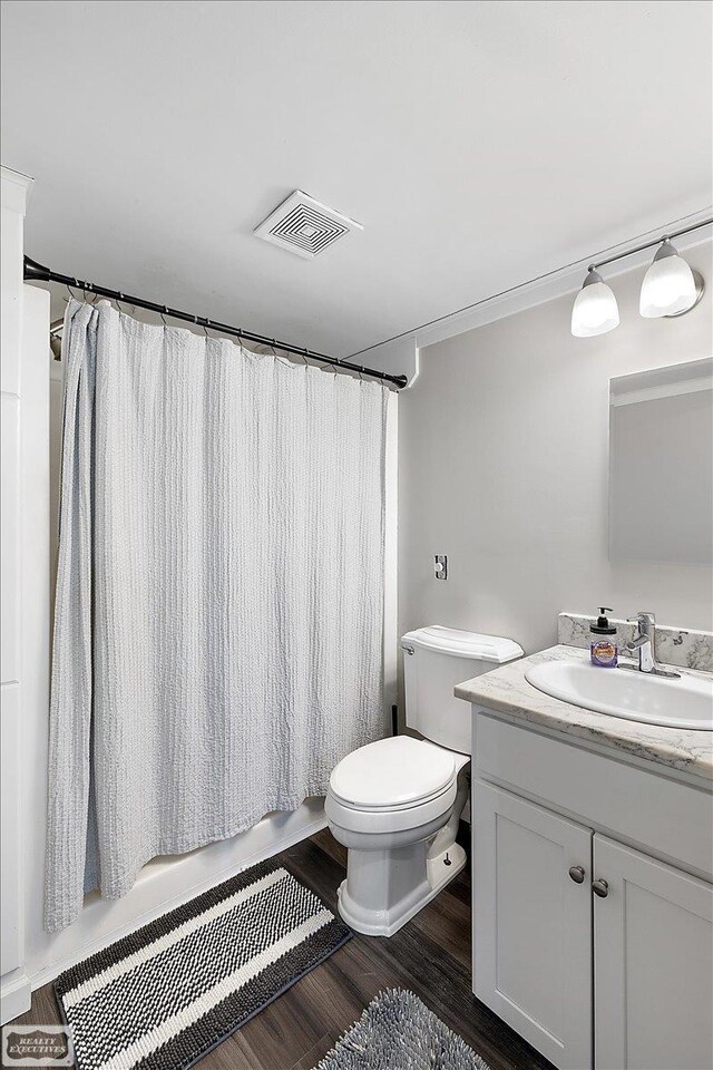 455 Garfield Rd, Fostoria, MI 48435 - bathroom featuring visible vents, wood finished floors, vanity, toilet, and shower / bathtub combination with curtain