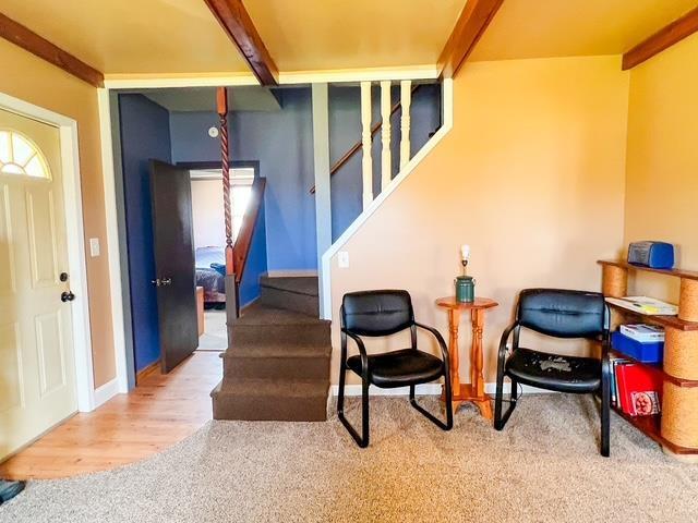 interior space featuring baseboards, stairs, beam ceiling, and wood finished floors