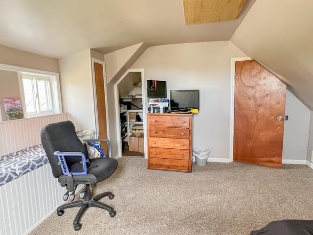 interior space with baseboards, carpet flooring, and vaulted ceiling