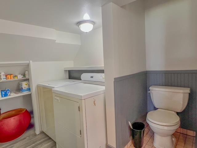 clothes washing area with separate washer and dryer, laundry area, and wainscoting