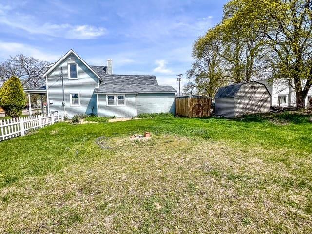 back of house featuring fence, an outbuilding, a lawn, and a shed