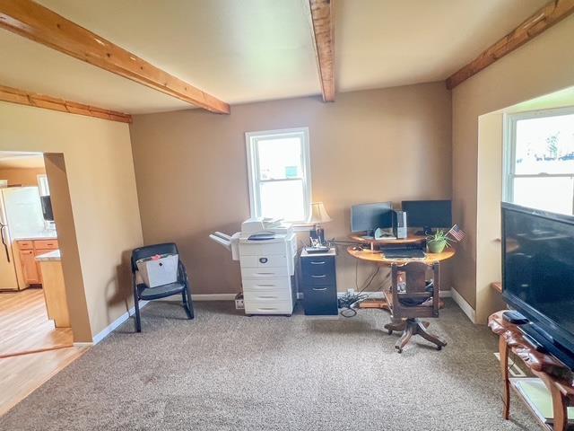 office area with baseboards, light carpet, and beam ceiling