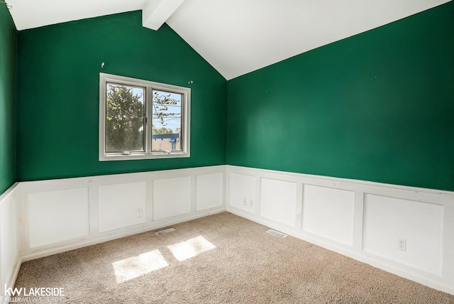 unfurnished room with visible vents, wainscoting, lofted ceiling with beams, a decorative wall, and carpet flooring