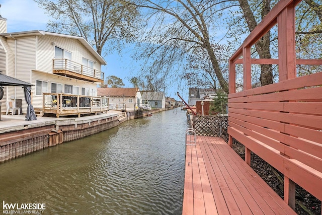 view of dock featuring a gazebo, a water view, and a balcony