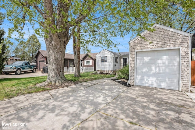 view of front facade with fence, driveway, and stone siding