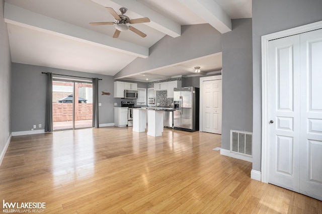 unfurnished living room with baseboards, ceiling fan, visible vents, and vaulted ceiling with beams