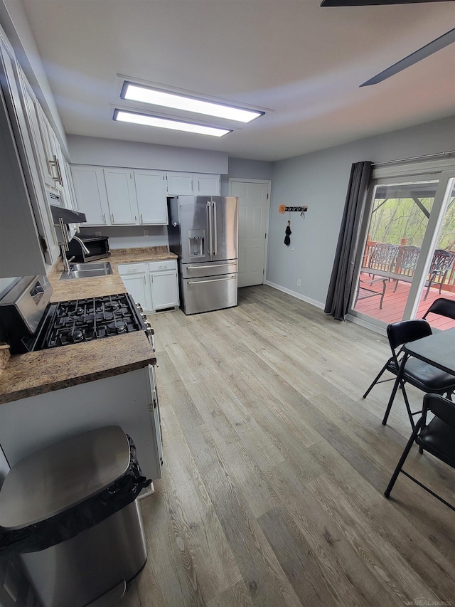 kitchen with white cabinets, stainless steel appliances, baseboards, and light wood finished floors