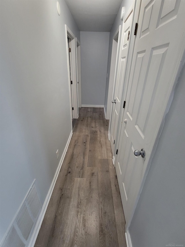 hallway with visible vents, baseboards, and wood finished floors
