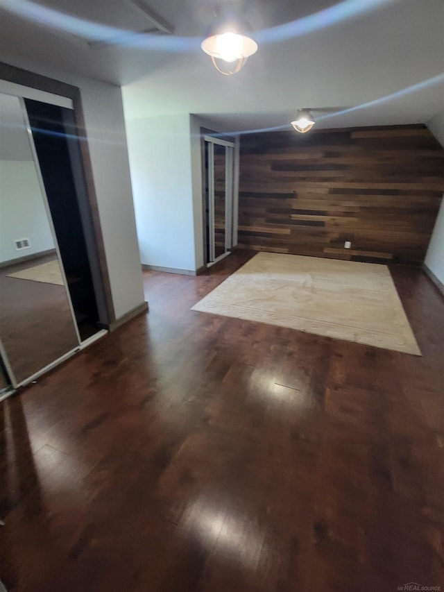 unfurnished dining area with baseboards, wood walls, and wood finished floors