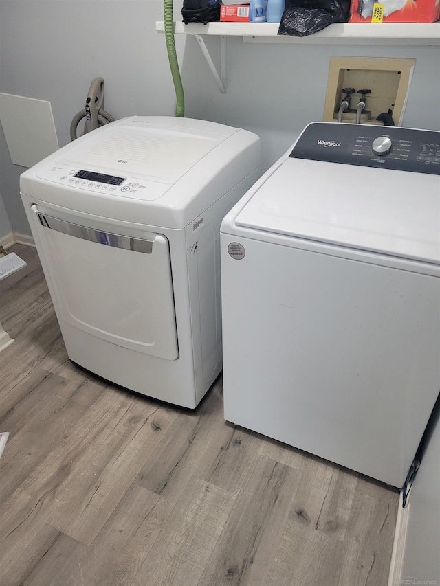 washroom featuring separate washer and dryer, laundry area, and light wood-type flooring