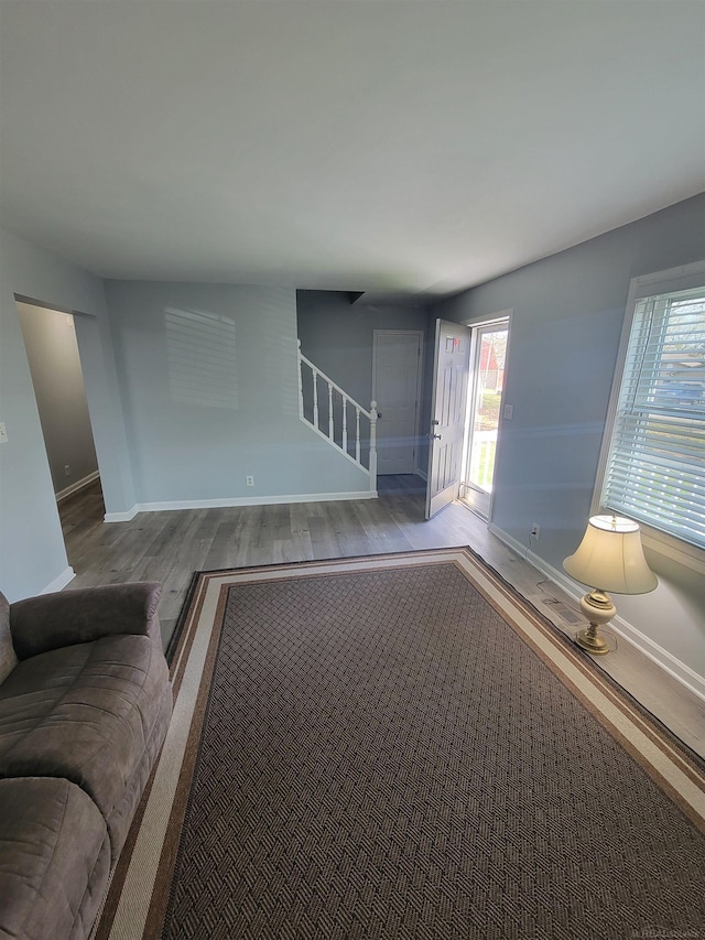 unfurnished living room with baseboards, stairs, and wood finished floors