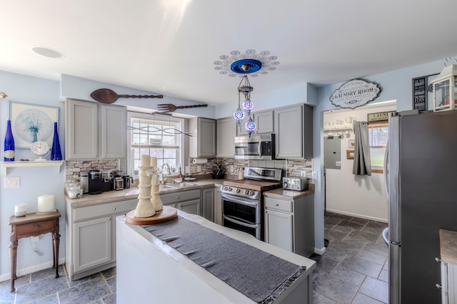 kitchen featuring backsplash, baseboards, appliances with stainless steel finishes, and gray cabinets