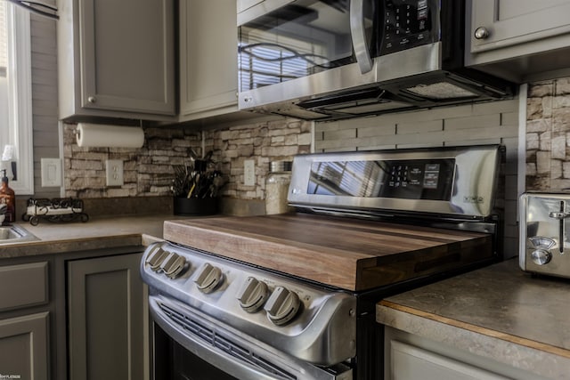 kitchen featuring gray cabinetry, appliances with stainless steel finishes, and backsplash