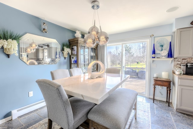 dining space featuring stone tile flooring, baseboards, and a baseboard heating unit