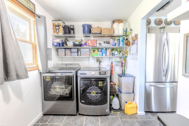 laundry room featuring washer and dryer, laundry area, stone finish flooring, and baseboards