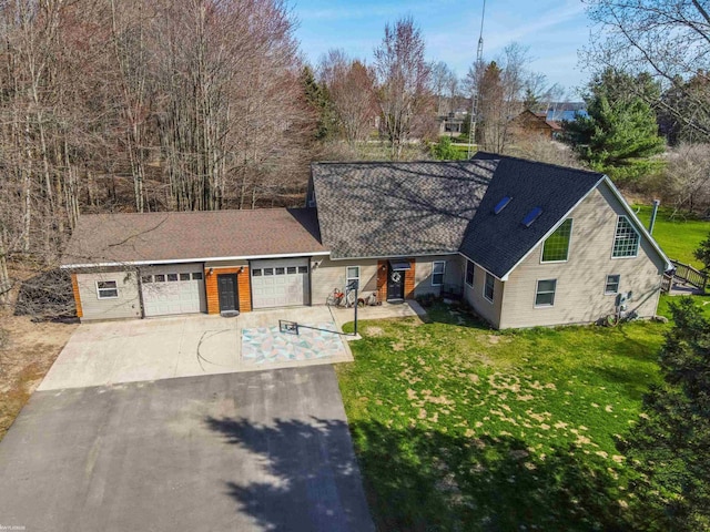 view of front of house featuring a shingled roof, an attached garage, concrete driveway, and a front yard
