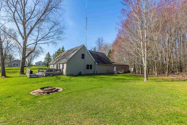view of property exterior featuring a yard, a wooden deck, and an outdoor fire pit