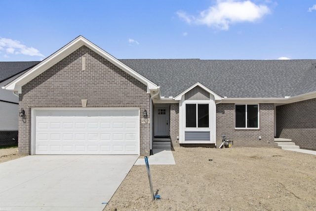 ranch-style house featuring roof with shingles, an attached garage, concrete driveway, and brick siding