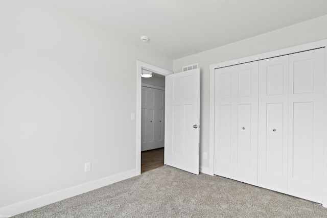 unfurnished bedroom featuring carpet floors, baseboards, visible vents, and a closet
