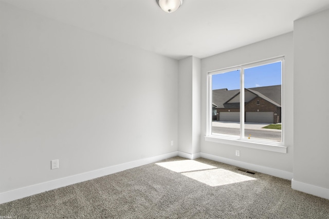 unfurnished room with baseboards, visible vents, and carpet