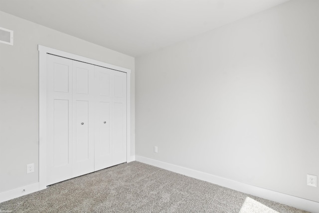 unfurnished bedroom with baseboards, carpet, and a closet