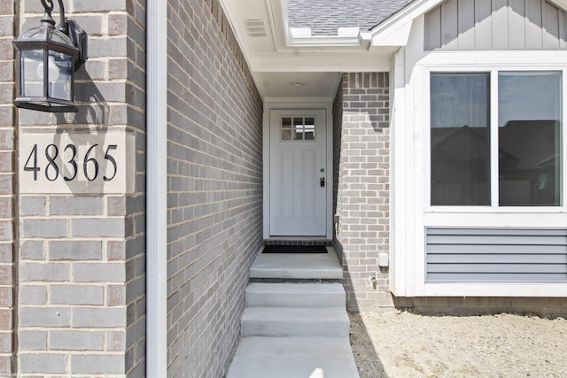 entrance to property with brick siding and roof with shingles