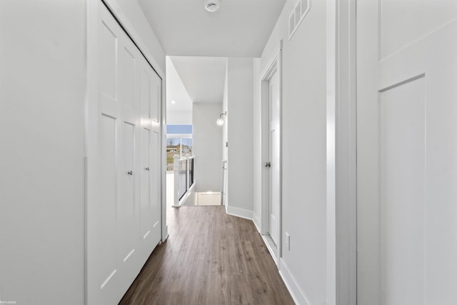 hall featuring visible vents, baseboards, and dark wood-type flooring