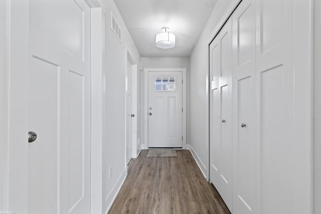 doorway to outside with baseboards, dark wood-style floors, and visible vents