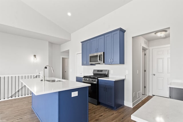 kitchen with a kitchen island with sink, blue cabinets, a sink, stainless steel appliances, and dark wood-type flooring