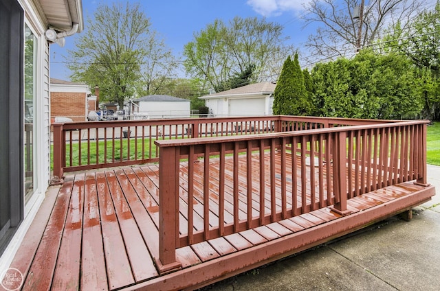 wooden terrace with an outdoor structure, a garage, and a lawn