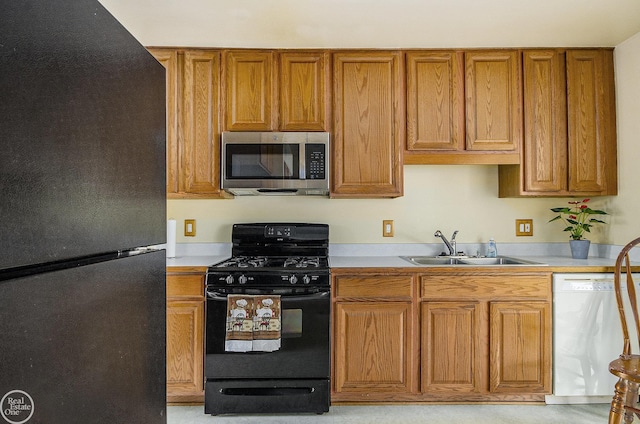 kitchen featuring brown cabinetry, a sink, black appliances, and light countertops