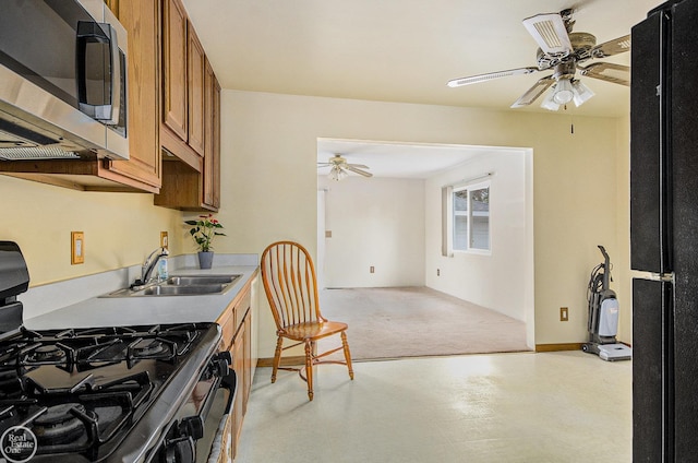 kitchen with a ceiling fan, stainless steel microwave, brown cabinetry, and gas stove