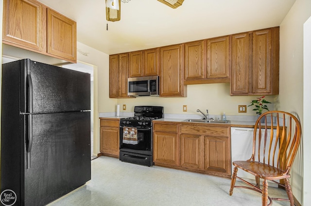 kitchen with a sink, light floors, brown cabinets, and black appliances