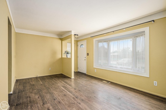 interior space featuring crown molding, baseboards, wood finished floors, and visible vents
