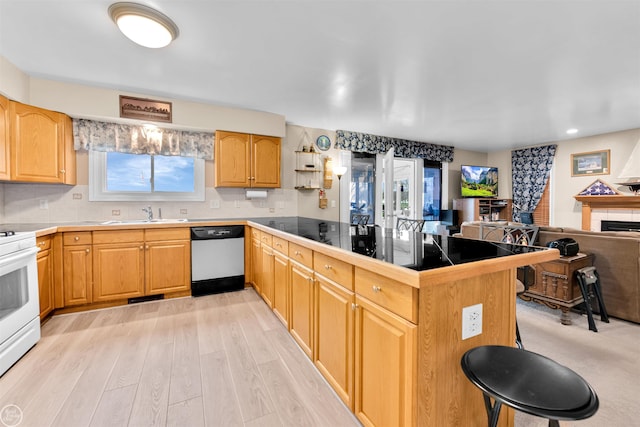 kitchen with white electric stove, dishwasher, a peninsula, open floor plan, and a breakfast bar