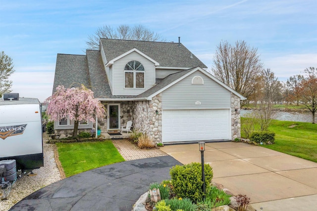 traditional-style home with driveway, a front yard, an attached garage, a shingled roof, and stone siding