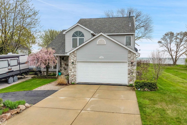 traditional-style home featuring a shingled roof, a front yard, stone siding, and concrete driveway